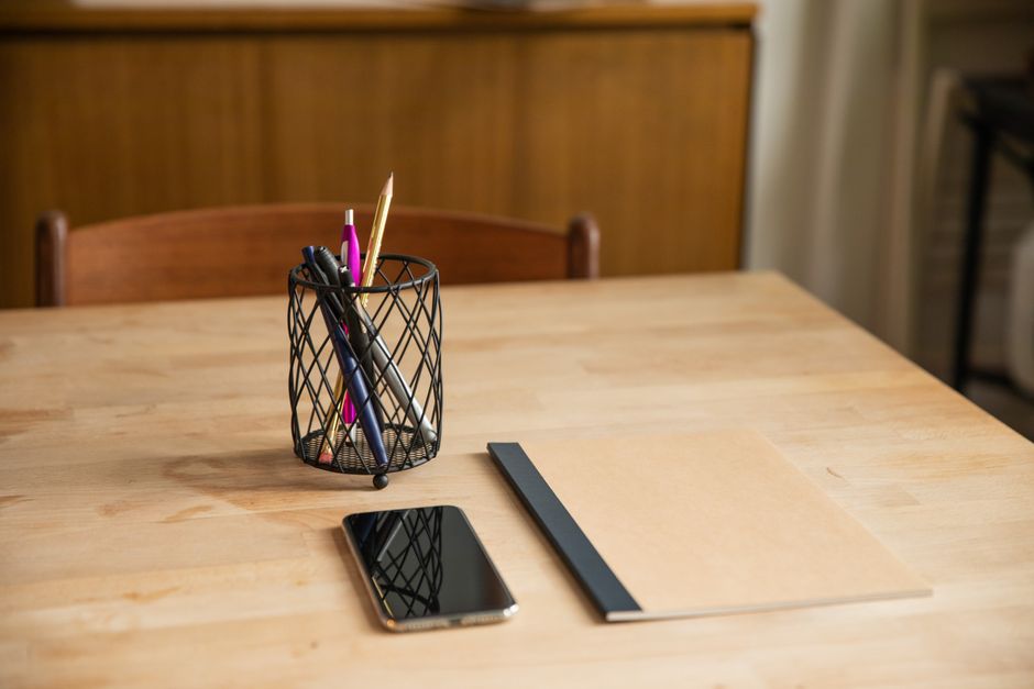 A tidy workspace featuring a wooden desk with a notebook, pens, and smartphone, ideal for productivity.